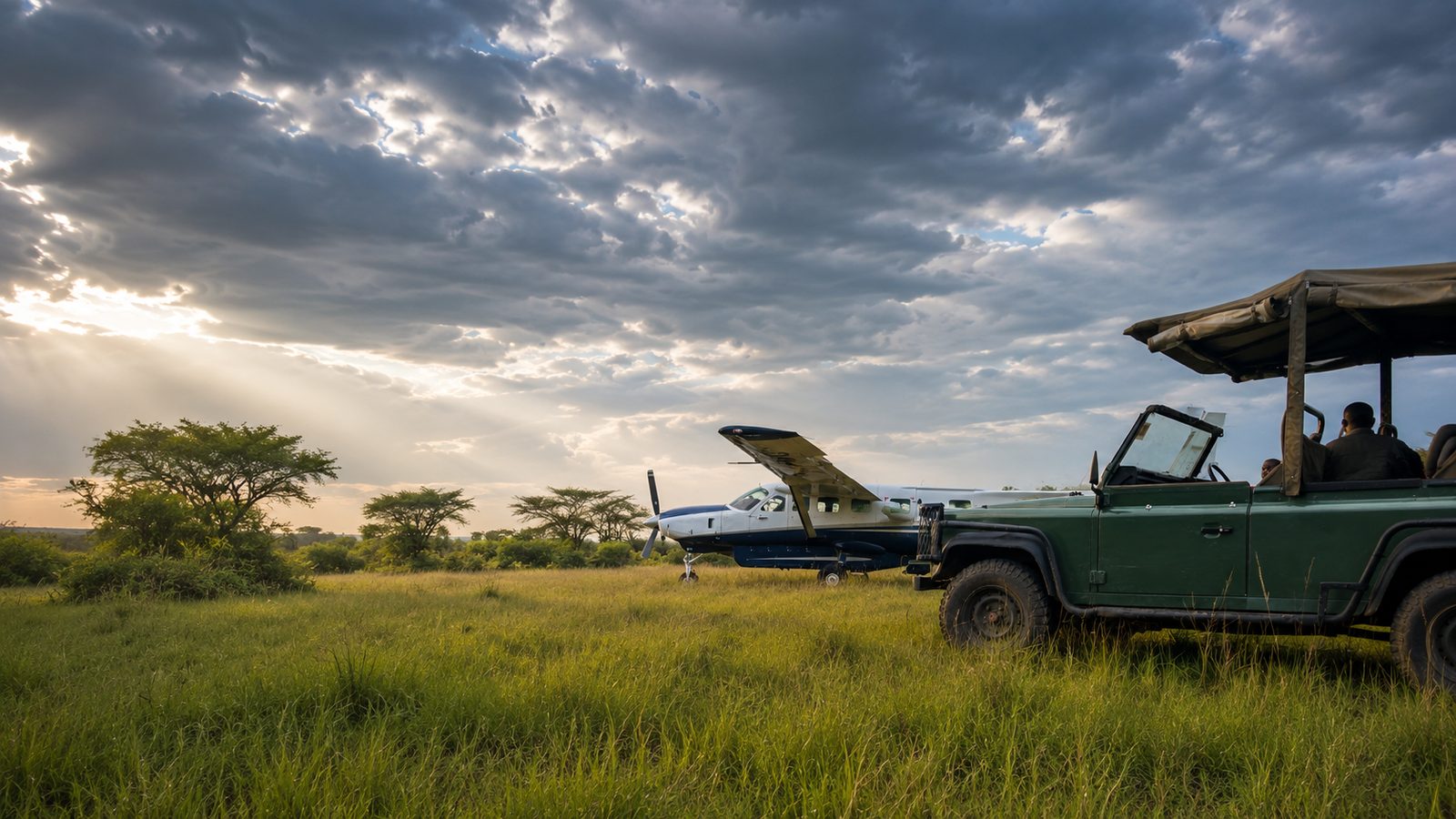 An Asante Aviation Grand Caravan and a safari vehicle on the savanna at golden hour