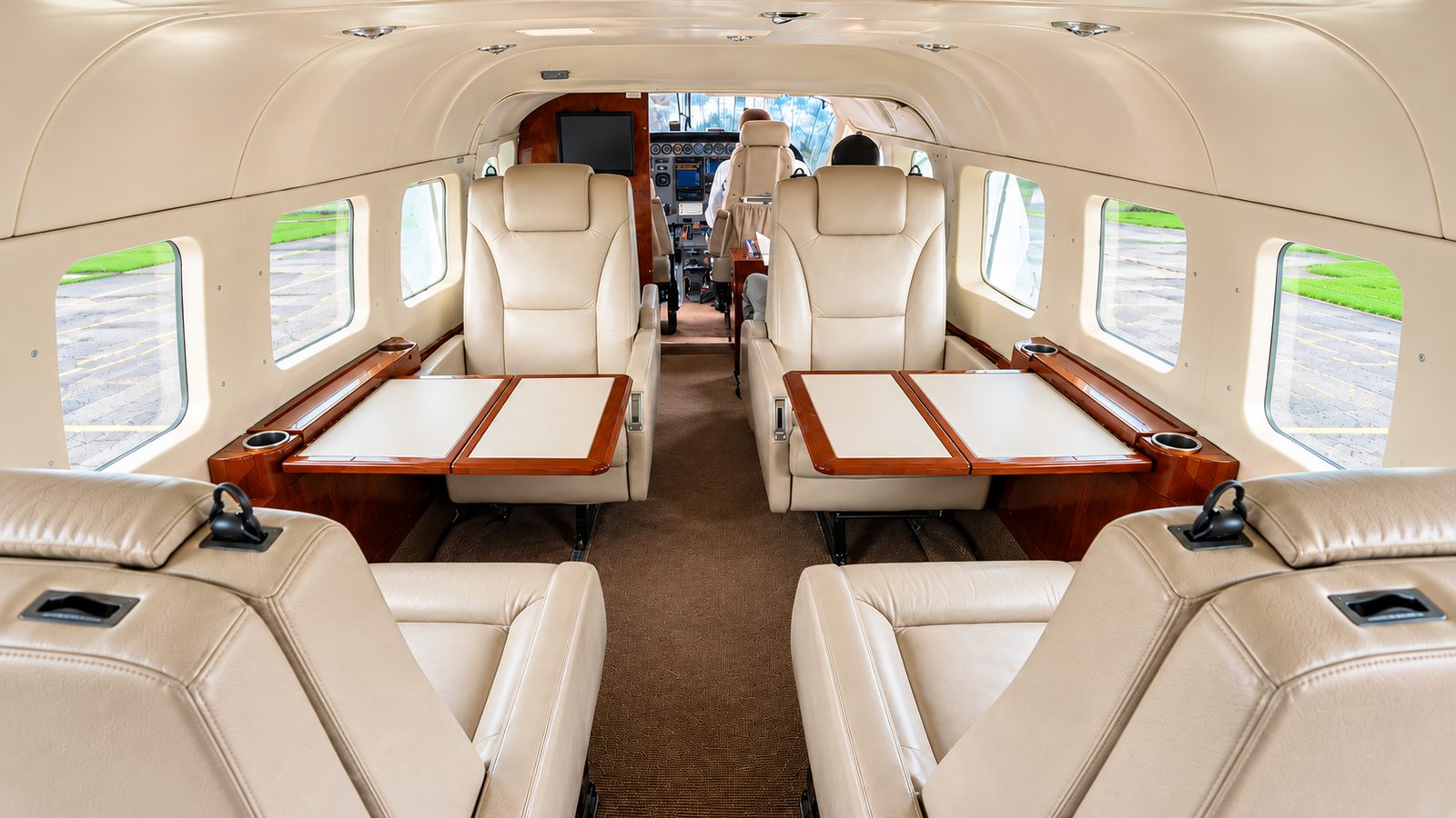 The cream-leather executive cabin of an Asante Aviation Grand Caravan, with club seating and burl-wood tables